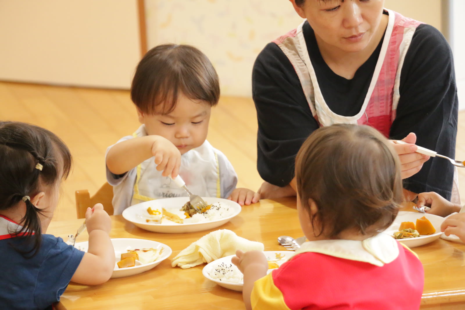 先生と一緒に給食を食べる子どもたち